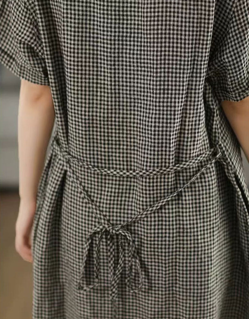 Person wearing a black and white checkered dress with a tie waist.