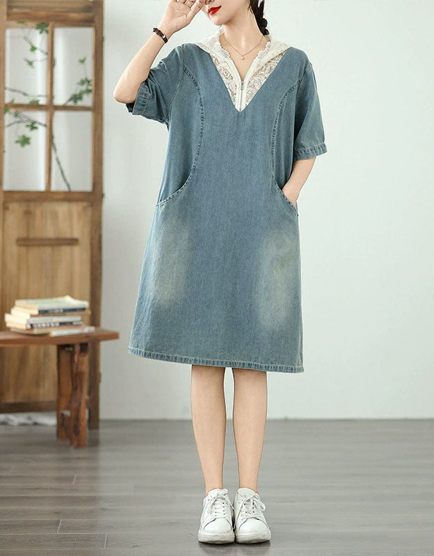 Woman wearing a denim dress with lace trim in a minimalistic room.