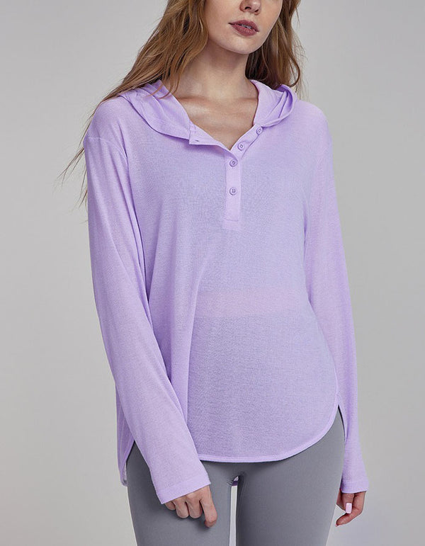 Woman wearing a light purple long-sleeve shirt with a hood on a gray background