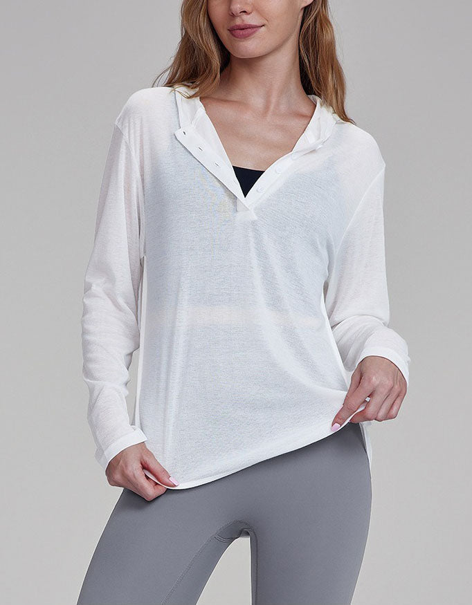 Woman wearing a white long-sleeve shirt and gray leggings on a gray background