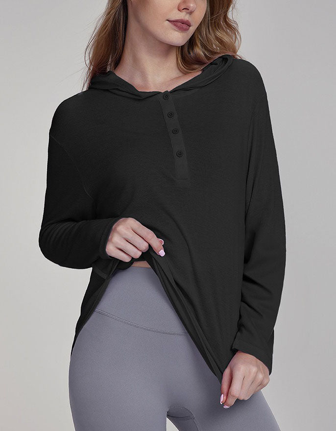 Woman wearing a black long-sleeve top and gray leggings on a plain background