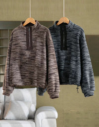 Two textured quarter-zip pullover sweaters hanging on wooden hangers. The sweater on the left is a heathered taupe-brown and gray, and the sweater on the right is a heathered dark gray and black.