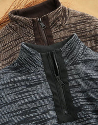 Close-up of a quarter-zip pullover sweater with a dark gray and white heathered knit body and a solid black zipper placket, shown layered over a brown and beige striped pullover.