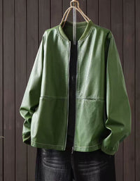 Green faux leather bomber jacket with zip-up front hanging against a dark wood panel background