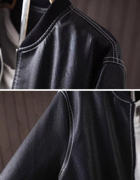 Close-up of black faux leather bomber jacket with zip-up front hanging against a dark wood panel background