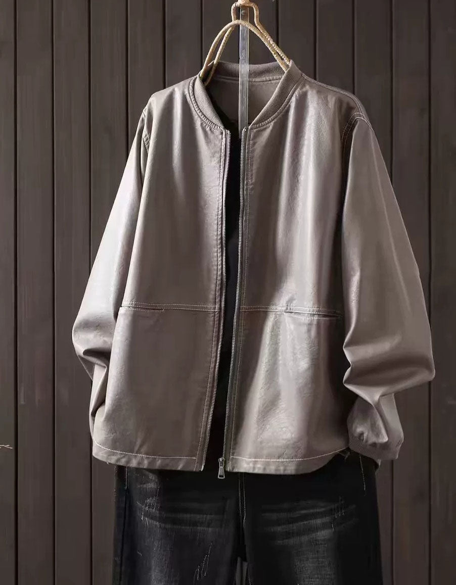 Gray faux leather bomber jacket with zip-up front hanging against a dark wood panel background