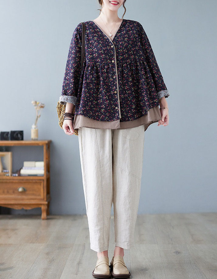 Person wearing a floral blouse and beige pants in a room with a gray wall and wooden furniture.