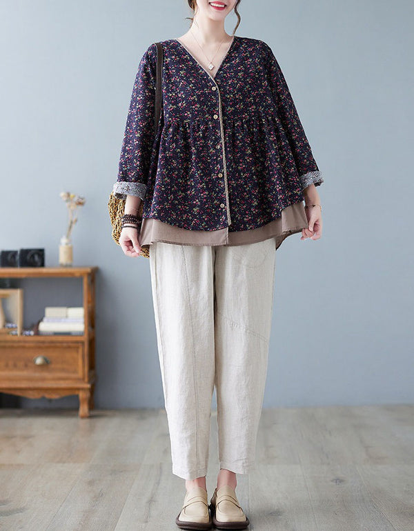 Person wearing a floral blouse and beige pants in a room with a gray wall and wooden furniture.