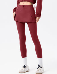 Person wearing a maroon outfit with a skirt and leggings on a white background