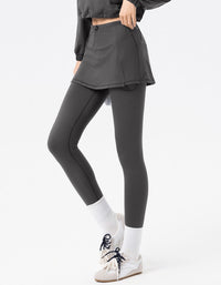 Person wearing gray leggings and a matching skirt on a white background