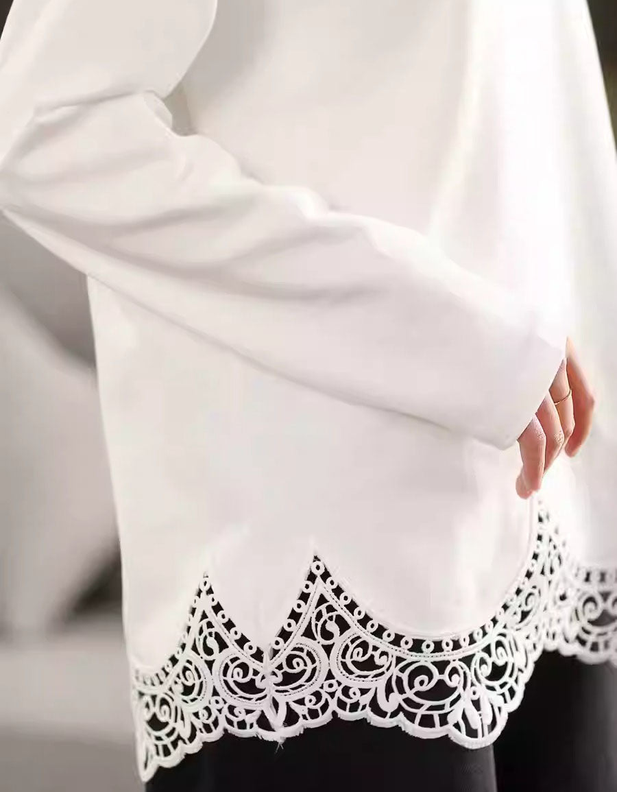 White blouse with intricate black lace detailing on a plain background