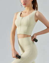 Woman wearing a beige athletic outfit holding dumbbells against a light gray background