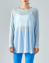 Woman wearing a light blue gradient long-sleeve top and bright blue leggings on a gray background