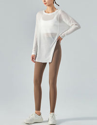 Person wearing a white long-sleeve top and brown leggings on a light gray background