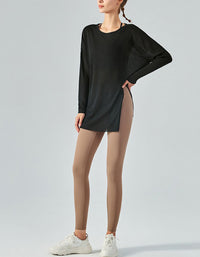 Person wearing a black long-sleeve top and beige leggings on a light gray background