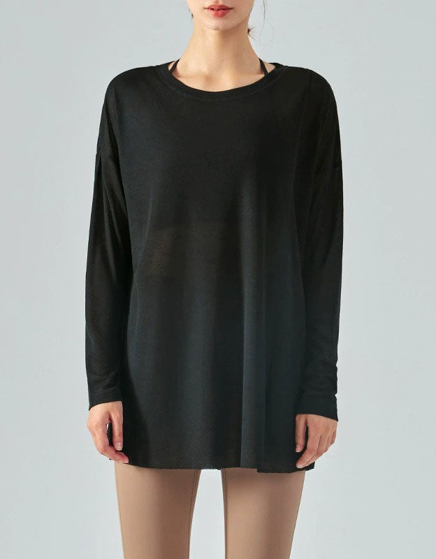 Black long-sleeve top worn by a person on a gray background