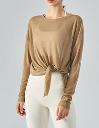 Woman wearing a brown long-sleeve top with a knot detail on a gray background