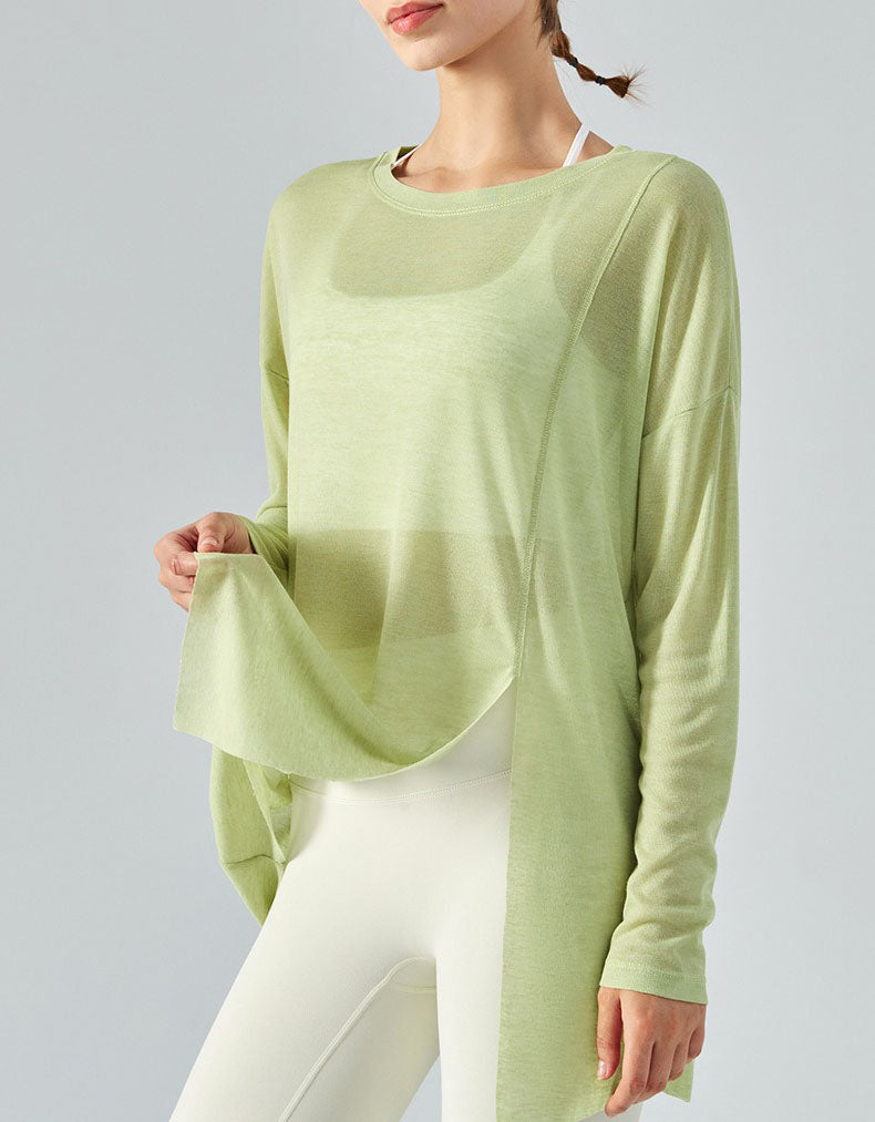 Person wearing a light green long-sleeve top and white pants on a gray background