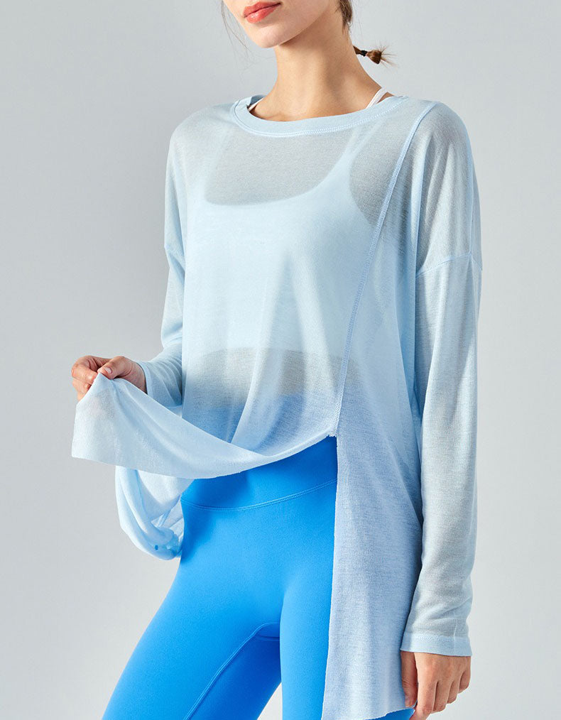 Woman wearing a light blue long-sleeve top and blue leggings on a gray background