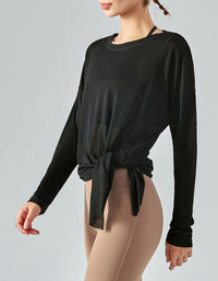 Person wearing a black long-sleeve top with a knot detail on a gray background