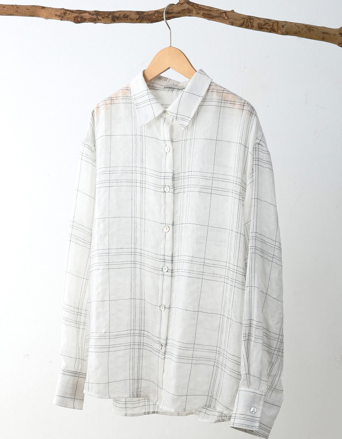 Plaid shirt on a hanger against a white background