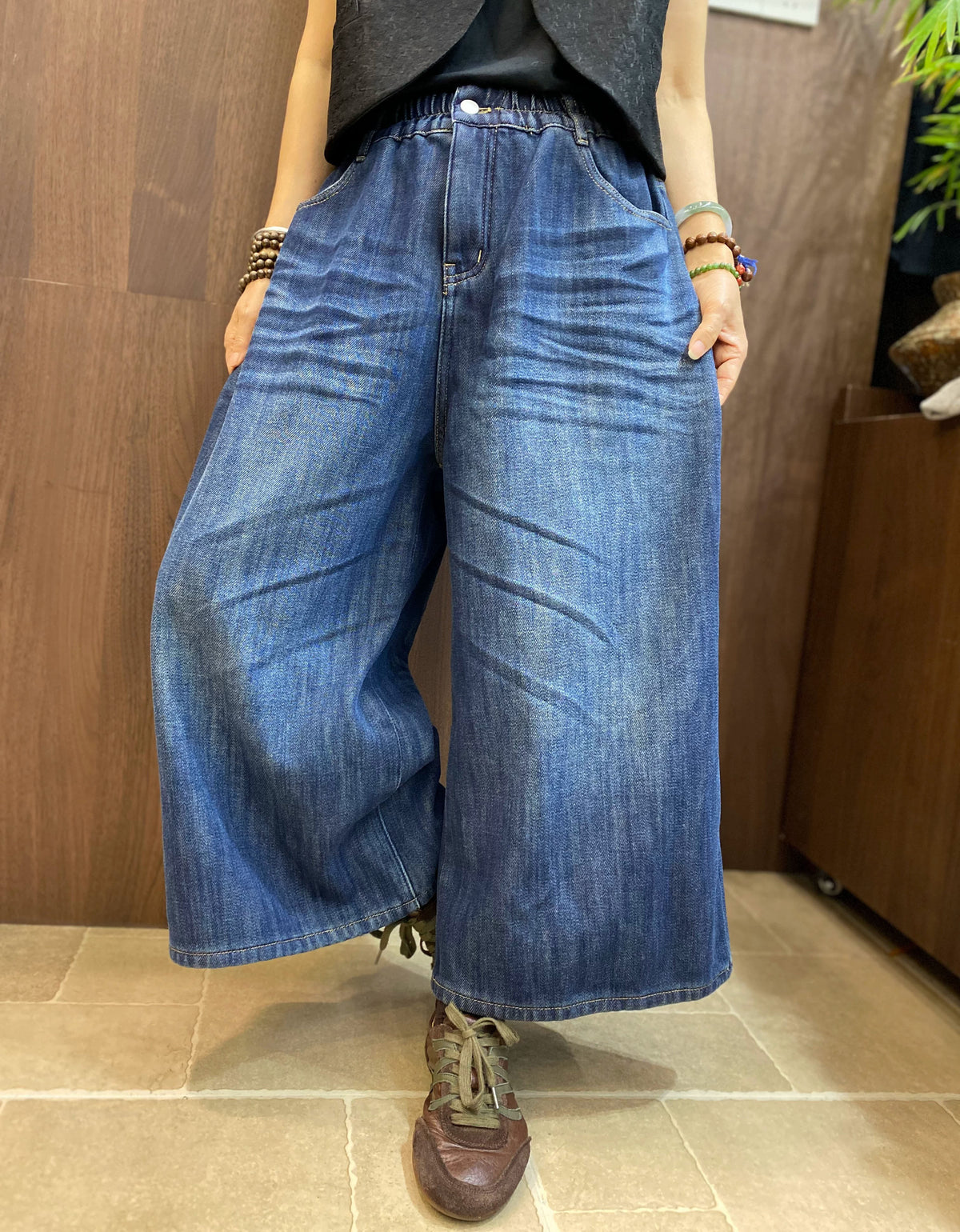 Elastic waistband and button fly detail of dark blue wide leg denim pants