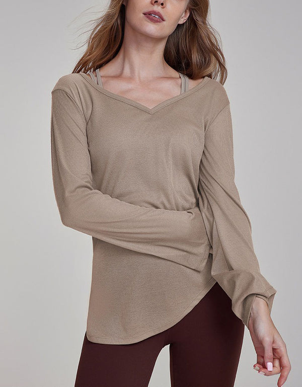 Woman wearing a beige long-sleeve top against a plain background