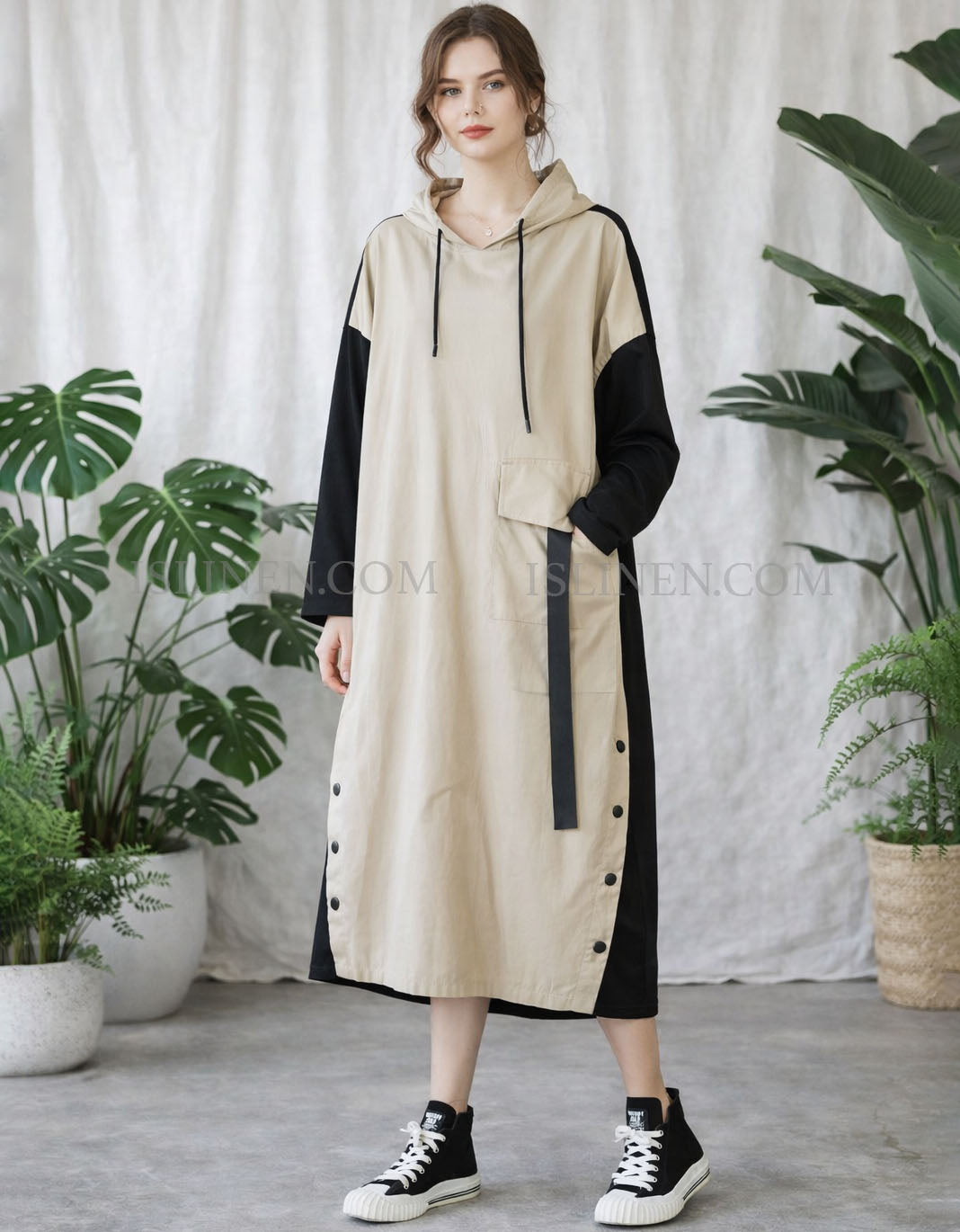 Woman wearing a beige and black dress with plants in the background
