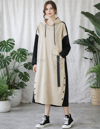 Woman wearing a beige and black dress with plants in the background