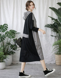 Woman wearing a black and gray dress with sneakers in a room with plants