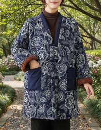 Woman wearing a dark blue patterned coat with brown cuffs against a beige wall.