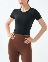 Person wearing a black short-sleeve top and brown leggings on a white background