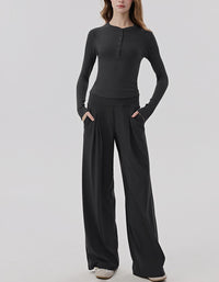 Person wearing a black long-sleeve top and wide-leg pants on a white background