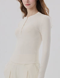Woman wearing a cream-colored long-sleeve top against a white background side view