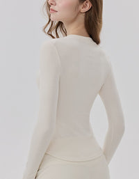 Woman wearing a white long-sleeve top against a plain background back view