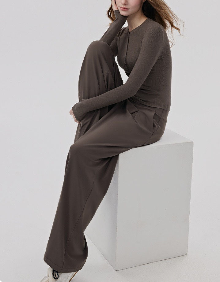 Person wearing a coffee outfit sitting on a white cube against a light gray background