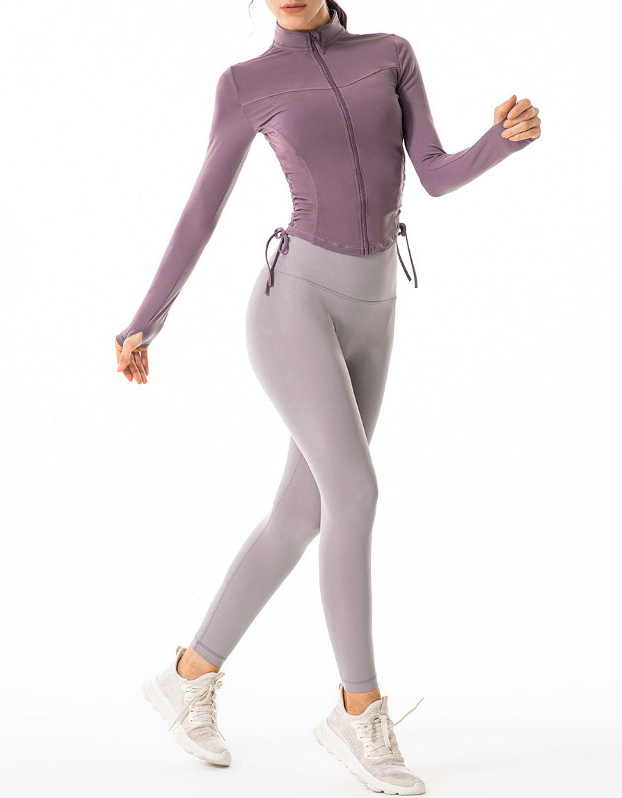 Person wearing a purple long-sleeve top and gray leggings on a white background