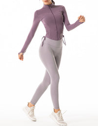 Person wearing a purple long-sleeve top and gray leggings on a white background