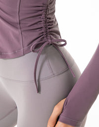 Close-up of a person wearing a purple top and gray leggings with a tie detail on a white background
