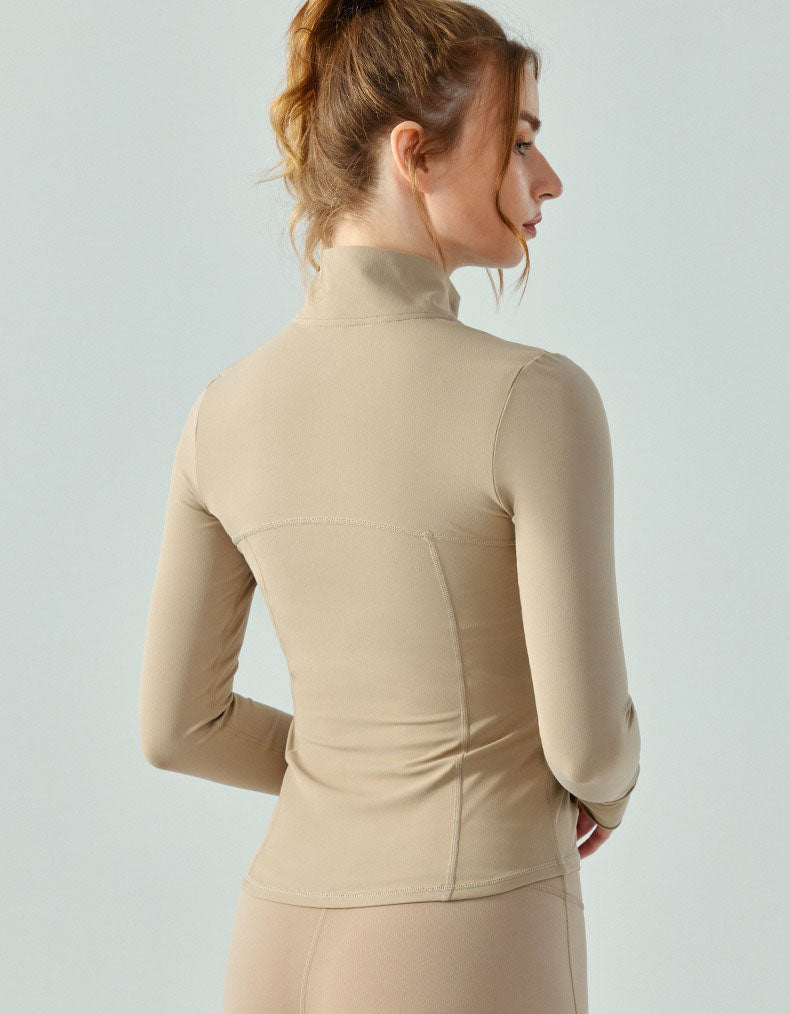 Woman wearing a beige turtleneck top against a light gray background back view