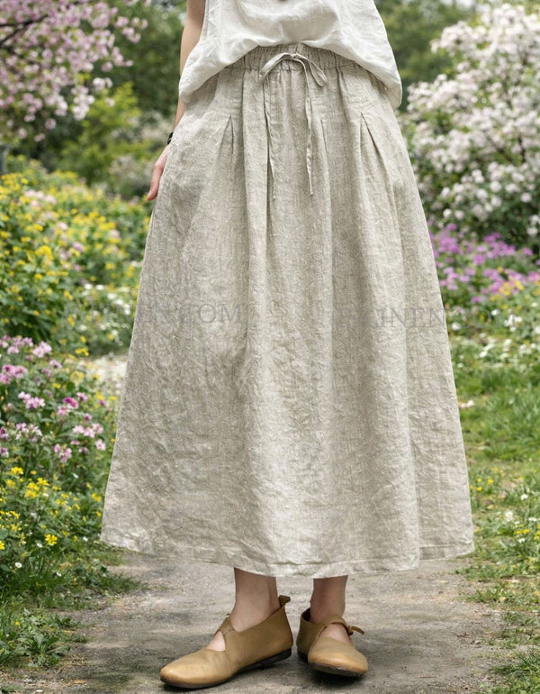 Woman wearing beige linen maxi skirt with pockets and elastic waist, styled with matching linen top in a garden path setting.
