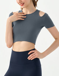 Woman wearing a gray crop top and navy leggings on a light gray background