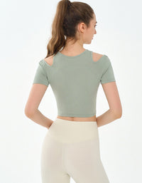 Woman wearing a green crop top and white pants on a light gray background