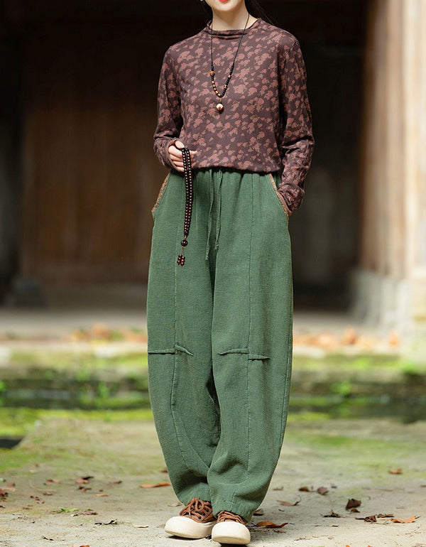 Green harem pants with a relaxed silhouette and rolled ankle cuffs, styled with brown casual shoes.
