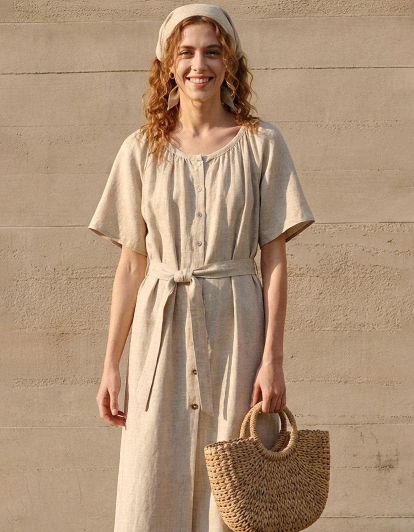 Woman wearing a beige dress holding a woven bag against a beige wall