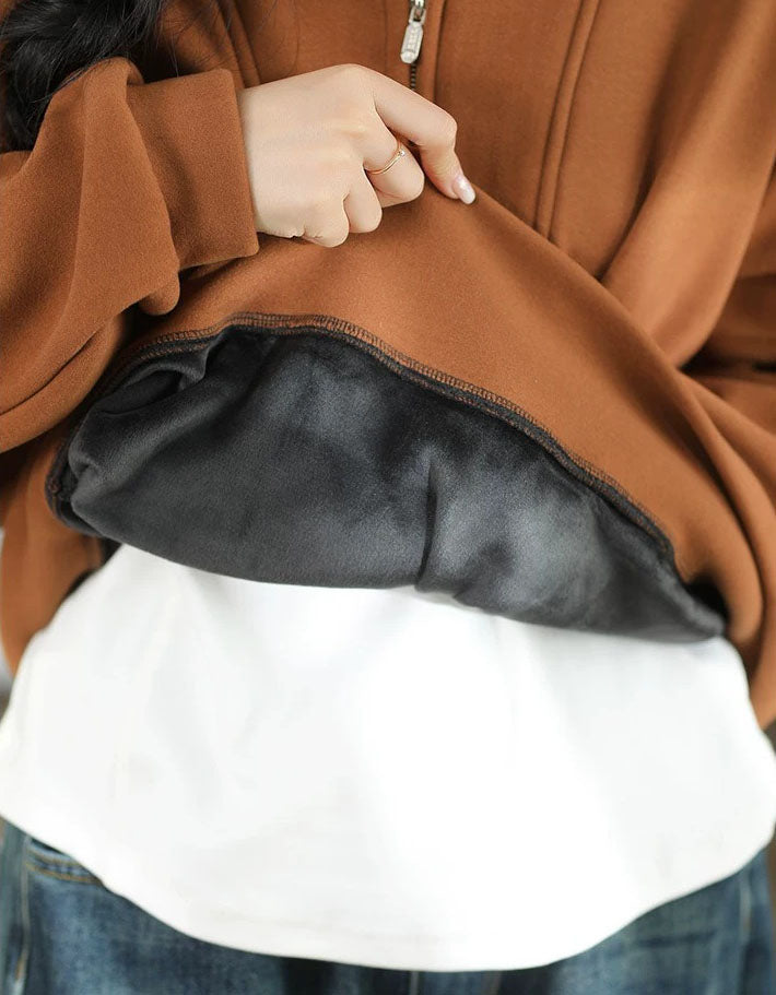 Women's brown quarter-zip sweatshirt styled with a white inner top and dark casual trousers