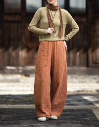 Woman wearing orange quilted wide leg pants with brown top and beige sneakers