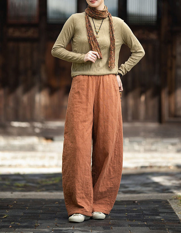 Woman wearing orange quilted wide leg pants with brown top and beige sneakers