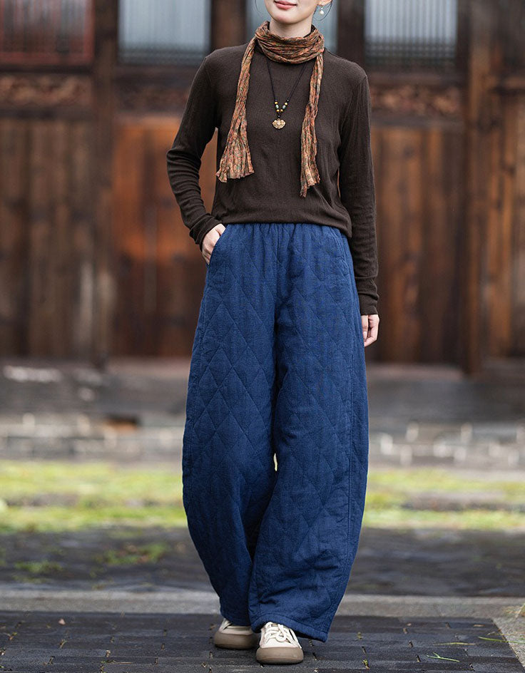 Woman wearing navy quilted wide leg pants with brown top and beige sneakers