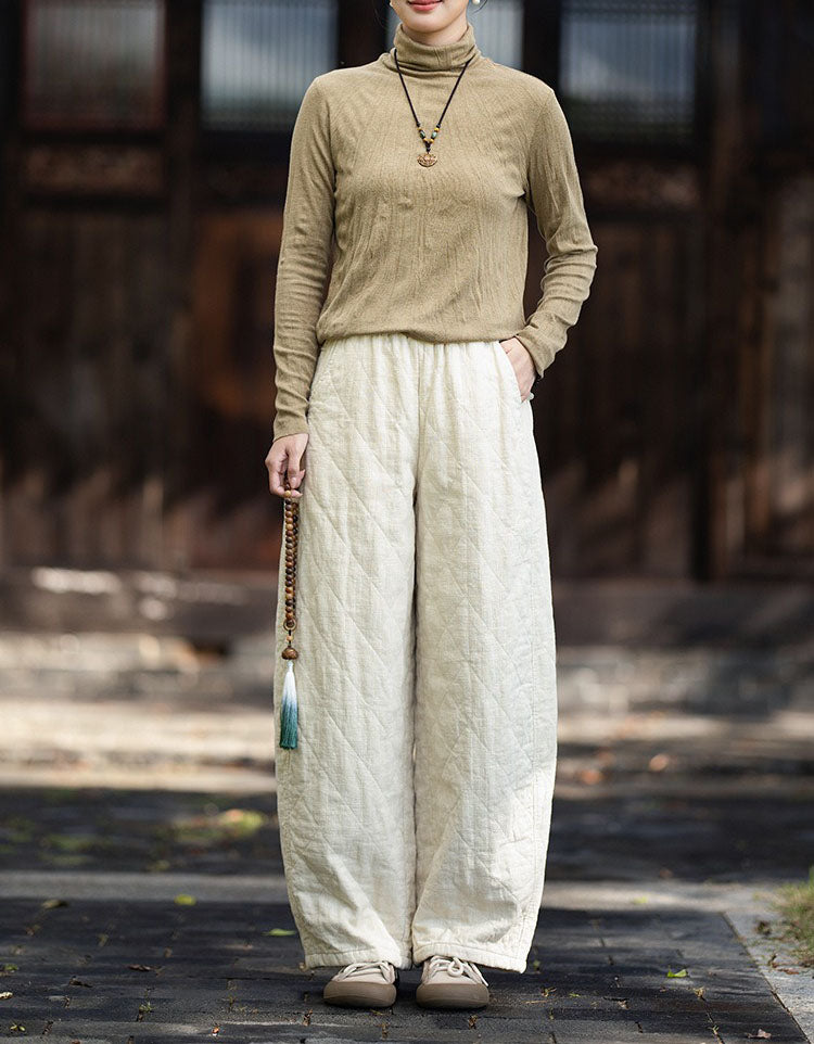 Woman wearing linen quilted wide leg pants with brown top and beige sneakers